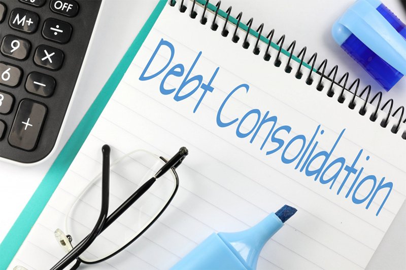 Debt Consolidation written on a notepad, lay on a desk.