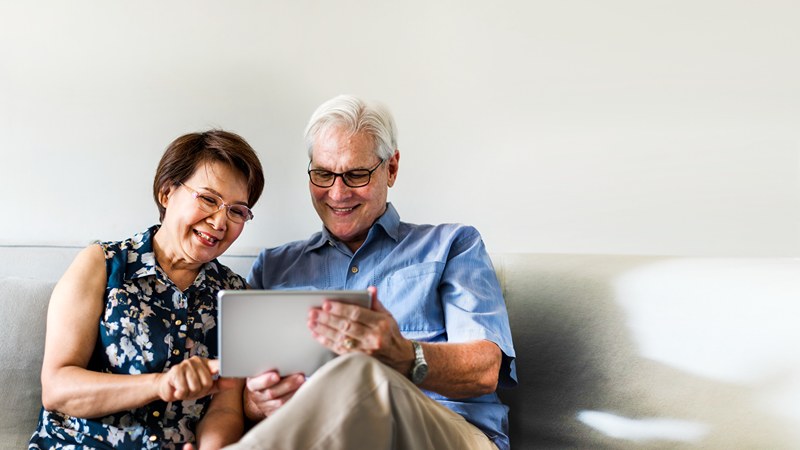 senior-couple-using-digital-device-living-room